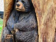 Close up of a chainsaw craving of a black bear sitting in a cavity of a tree