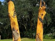 Two chainsaw carvings depicting several birds and animals all around them
