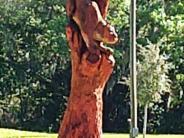 A chainsaw carving of a Florida Panther jumping down a tree 