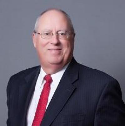 Kent Adcock wearing a blue blazer on top of a white shirt and red tie