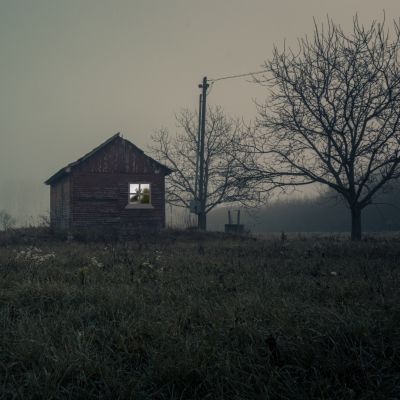 spooky cabin in the fog with a shadowy handprint in the window